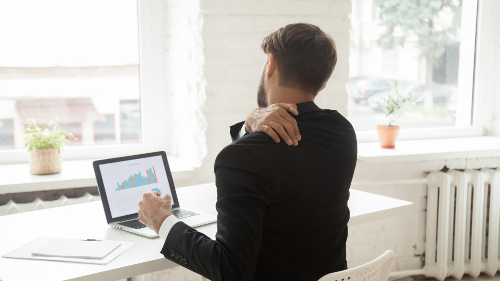 homme derrière un portable a une douleur à l'épaule