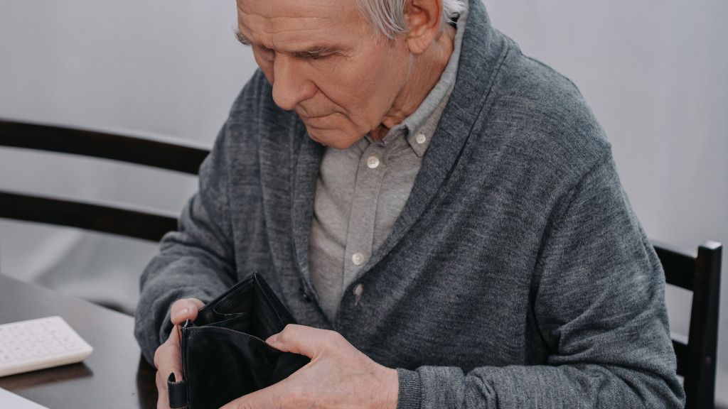 Monsieur âgé consultant son portefeuille vide