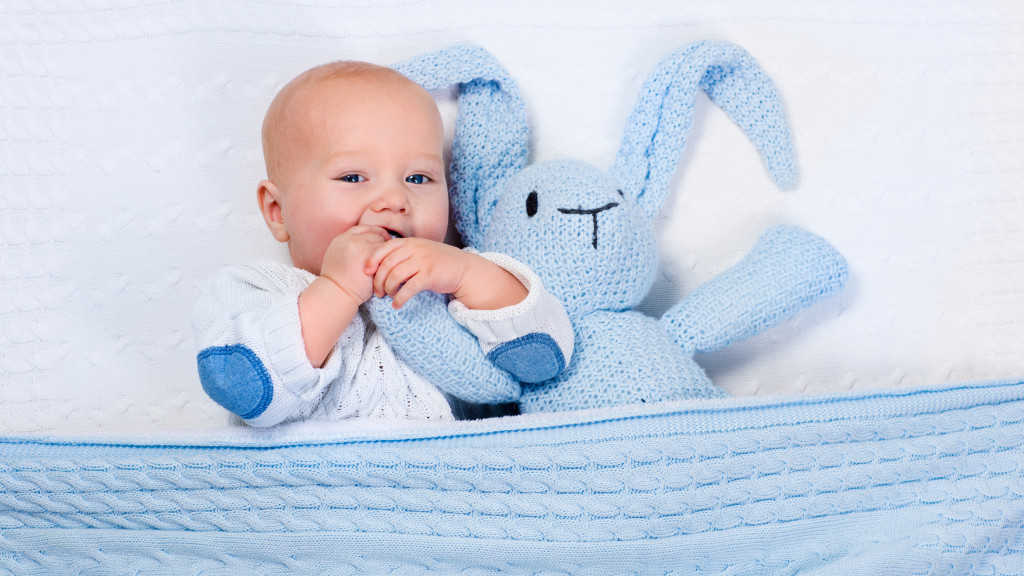 Baby met blauwe knuffel in bed
