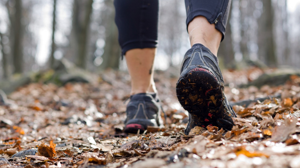 Personne qui marche en tenue de sport et baskets sur des feuilles 