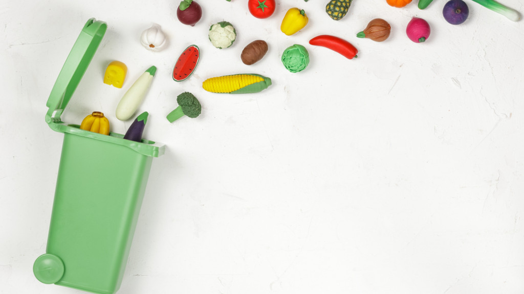 Divers légumes jetés en direction d'une poubelle verte