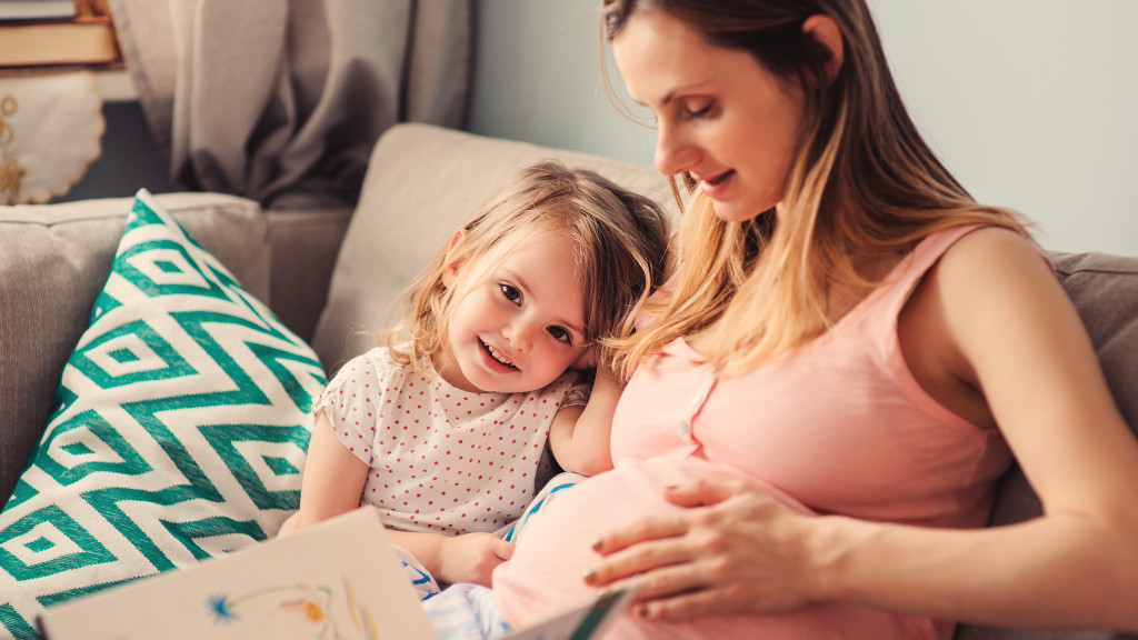 Femme enceinte avec enfant en bas âge assises dans un canapé