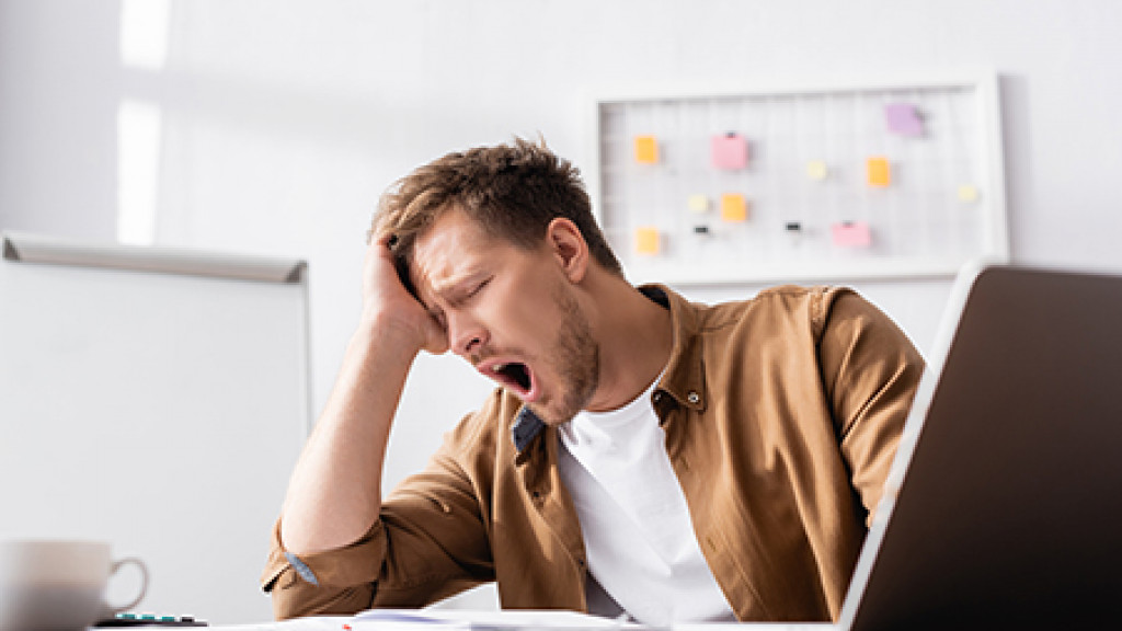 Geeuwende man achter laptopscherm