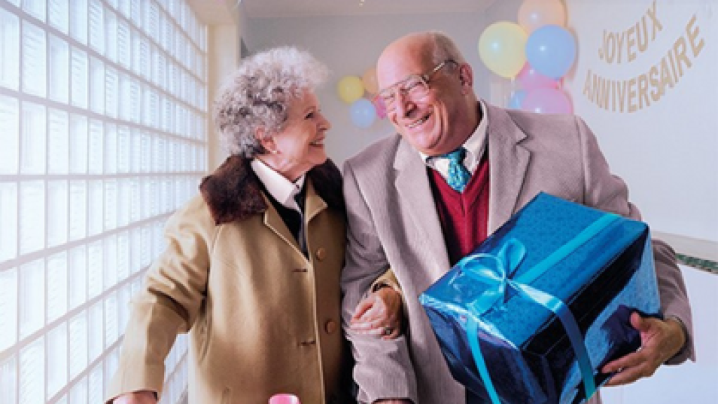 couple âgé avec un cadeau. Profitez de chaque moment grâce à la vaccination! 