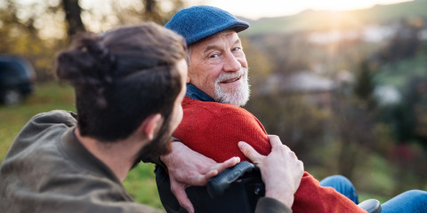 Oude man met pet in rolstoel
