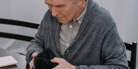 Monsieur âgé consultant son portefeuille vide