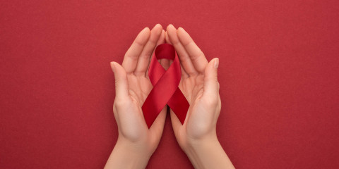 Mains tenant un ruban rouge avec arrière-plan rouge