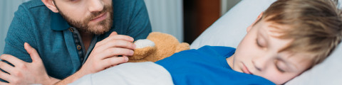 Enfant malade hospitalisé qui dort avec son papa à son chevet