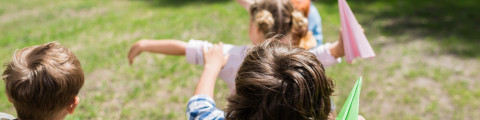 Kinderen spelen buiten en gooien met papieren vliegtuigjes