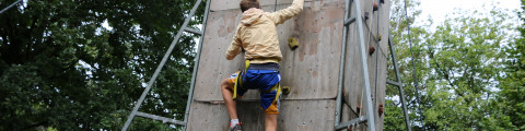 Kind klauwert op klimmuur tijdens jongerenkamp zomervakantie