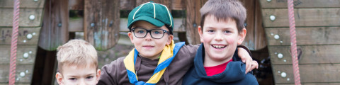 Drie jongens op het speelplein in uniform van de Chiro en de scouts