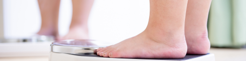 Vrouw met overgewicht staat op weegschaal - detailfoto 