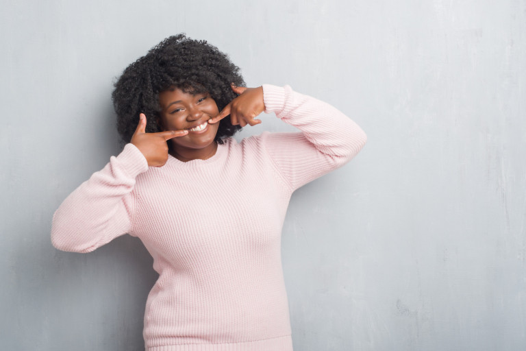 Vrouw met roze pullover en brede glimlach
