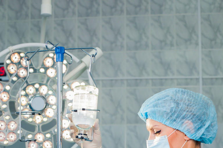 Infirmière ajustant une bouteille de perfusion dans un bloc opératoire