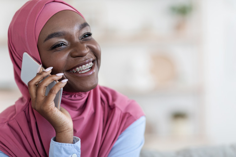 Une femme musulmane avec un sourire et un smartphone