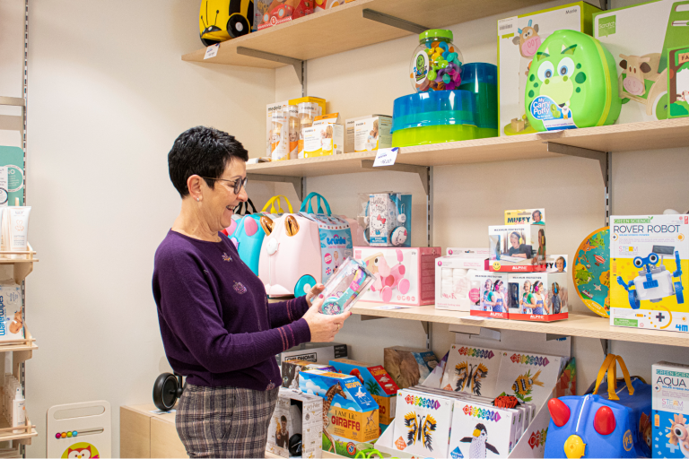 Medewerkster in de winkel van Zorgboetiek in Aalst aan het rek met babyproducten.