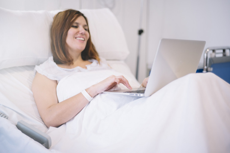 vrouw in bed ziekenhuis met laptop