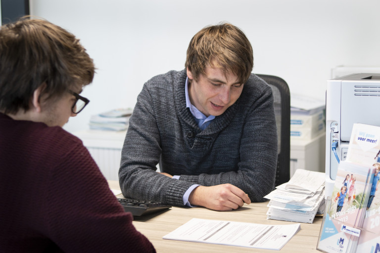 Kantoormedewerker geeft tijdens afspraak uitleg aan lid