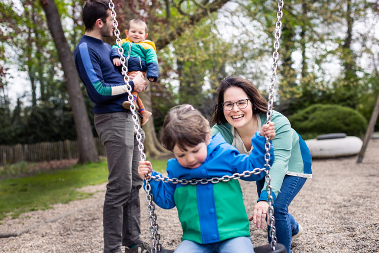Gezin van vier in de speeltuin op de schommel