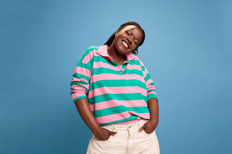 Jonge vrouw van poseert en lacht naar de camera