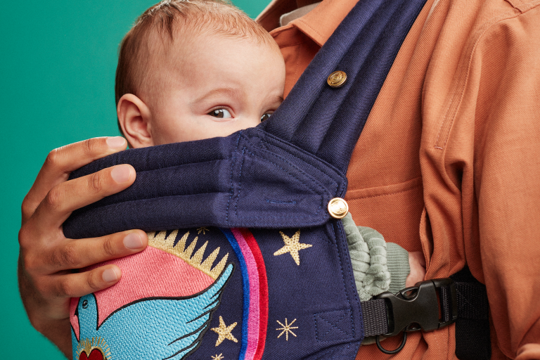 Baby in draagzak, piept naar de camera