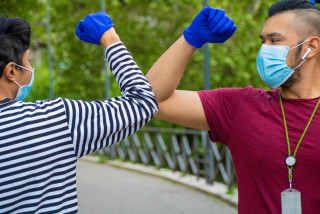 deux hommes se disent bonjour avec le coude en période de coronavirus