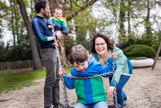 Gezin van vier in de speeltuin op de schommel