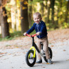 Kind op loopfiets in de herfst